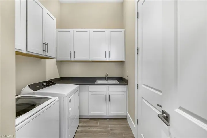 Clothes washing area featuring sink, cabinets, washing machine and clothes dryer, and light hardwood / wood-style floors