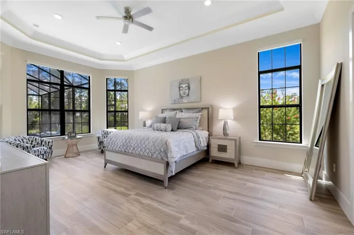 Bedroom featuring a tray ceiling, ceiling fan, and light hardwood / wood-style floors