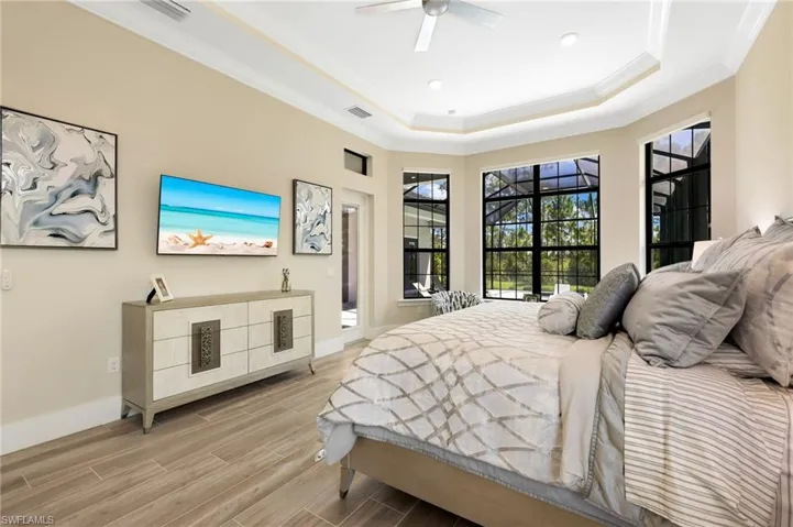 Bedroom with ceiling fan, crown molding, a raised ceiling, and light hardwood / wood-style floors