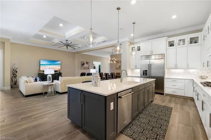 Kitchen featuring a center island with sink, tasteful backsplash, beamed ceiling, coffered ceiling, and sink