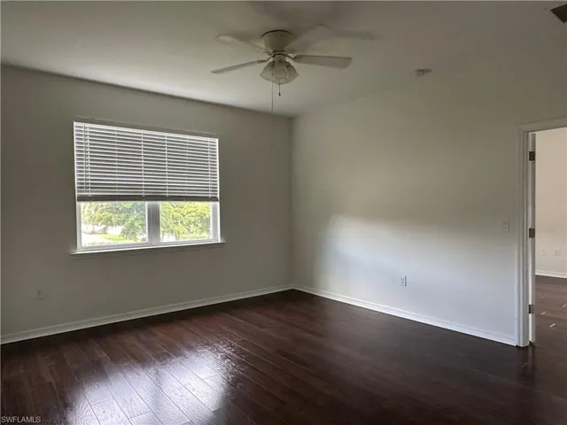 Empty room featuring ceiling fan and dark hardwood / wood-style floors