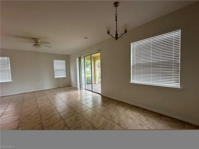 Unfurnished room featuring light tile patterned flooring and ceiling fan with notable chandelier