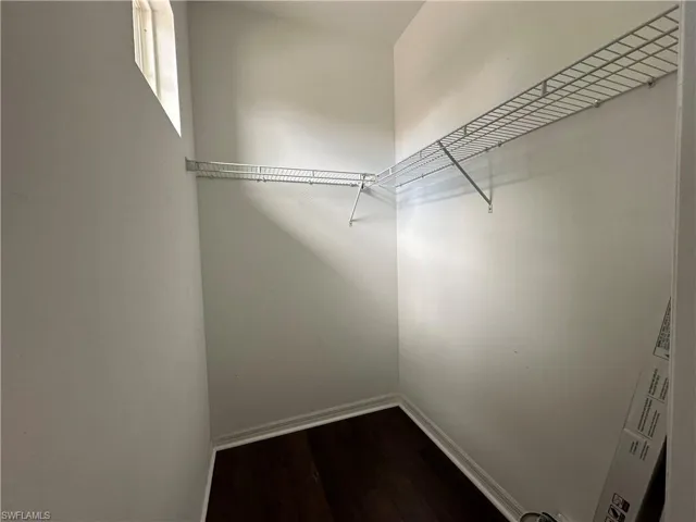 Walk in closet with hardwood / wood-style floors