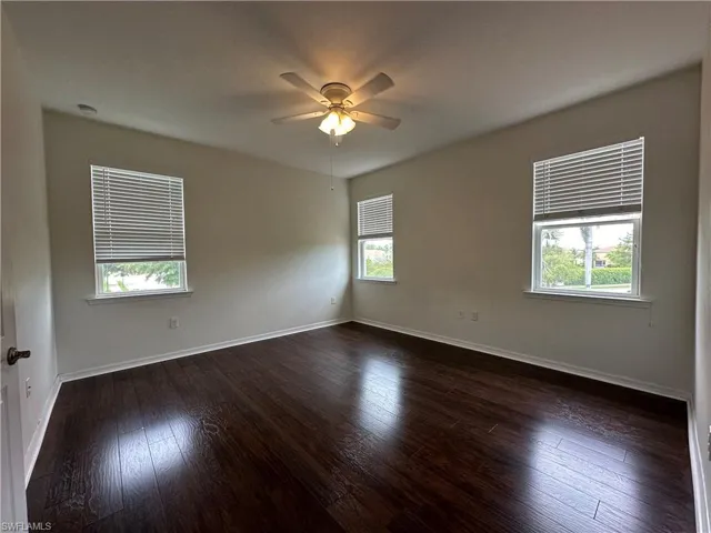 Unfurnished room featuring dark hardwood / wood-style flooring, a wealth of natural light, and ceiling fan