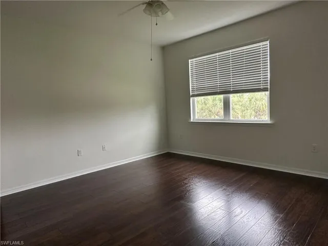 Empty room featuring ceiling fan and dark wood-type flooring