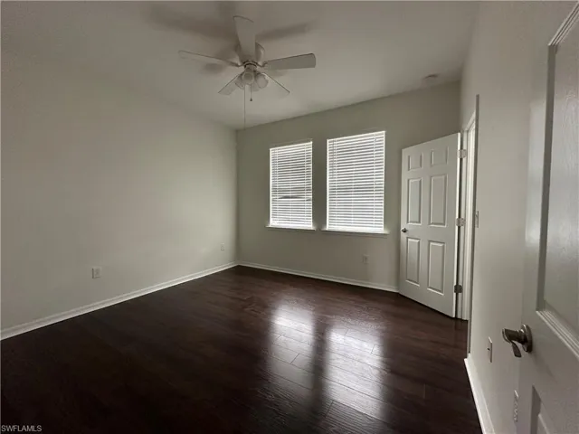 Empty room featuring ceiling fan and dark hardwood / wood-style floors