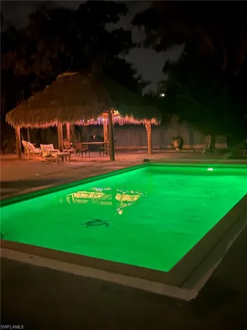 Pool at night with an outdoor pool and a patio
