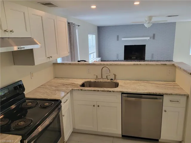 Kitchen featuring black range with electric stovetop, white cabinetry, stainless steel dishwasher, light stone counters, and a ceiling fan