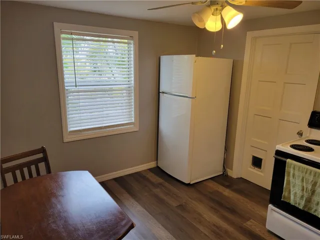 Kitchen with white appliances, ceiling fan, and dark wood-type flooring