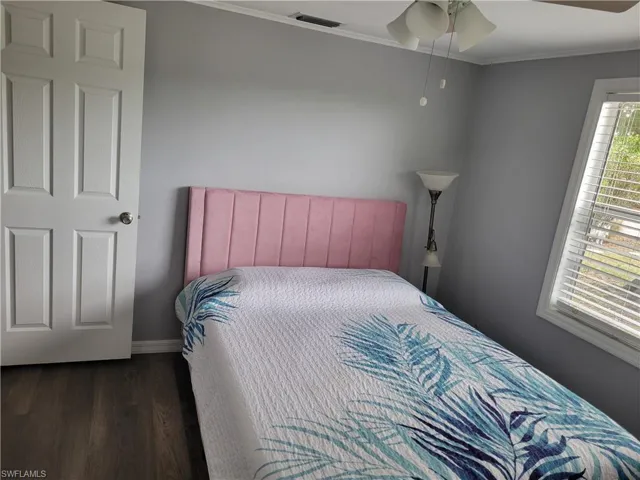 Bedroom with ornamental molding, wood finished floors, and ceiling fan