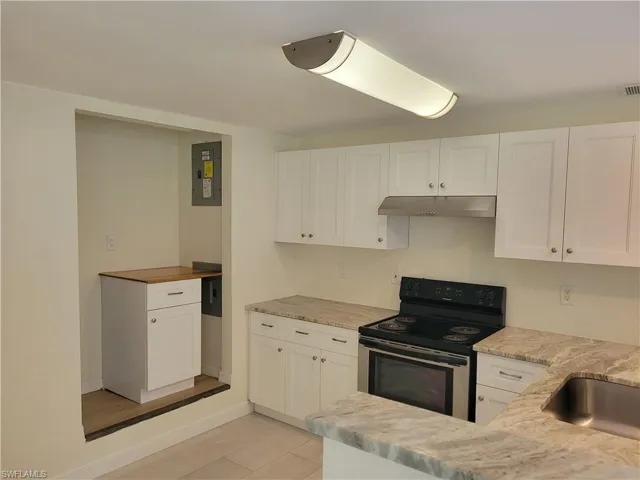Kitchen with range with electric cooktop, white cabinets, electric panel, and light stone countertops