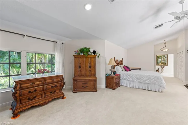 Bedroom featuring lofted ceiling, light carpet, and a ceiling fan