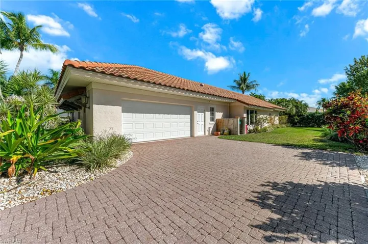 View of front of house featuring an attached garage, a front lawn, stucco siding, decorative driveway, and a tile roof
