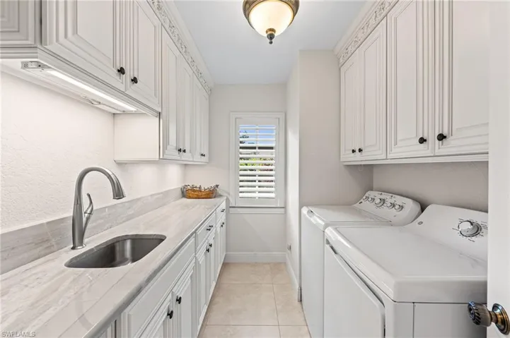 Laundry area with washing machine and dryer, cabinet space, and light tile patterned flooring