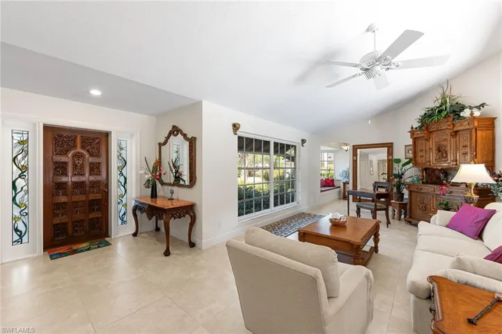 Living room featuring ceiling fan, light tile patterned floors, and a high ceiling