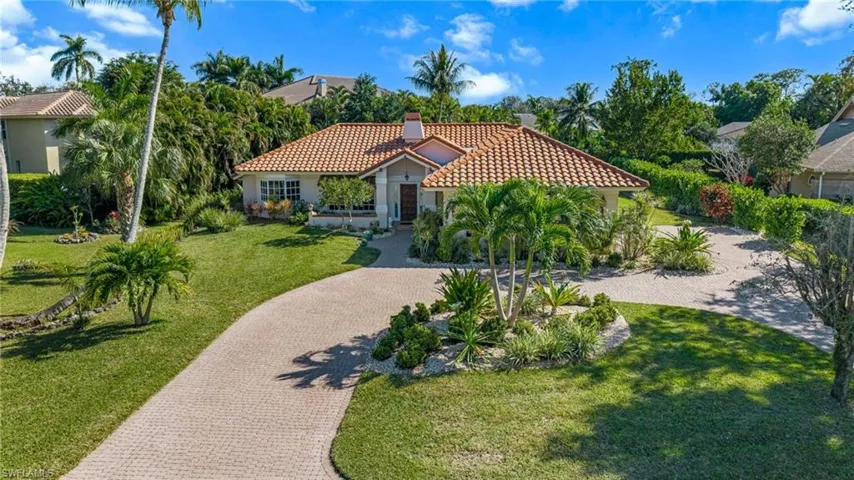 Mediterranean / spanish-style house with a tile roof, decorative driveway, stucco siding, a front lawn, and a chimney
