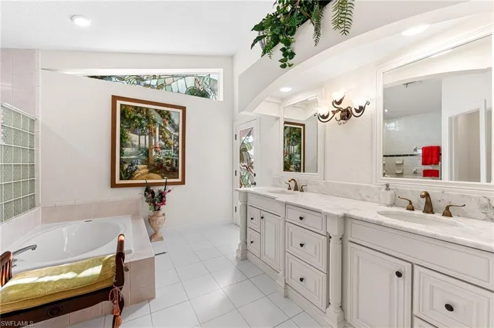 Bathroom with a bath, double vanity, light tile patterned floors, a chandelier, and recessed lighting