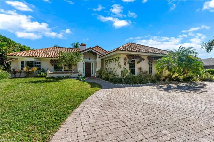 Mediterranean / spanish-style home featuring stucco siding, a tile roof, a chimney, and decorative driveway