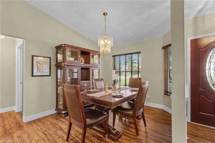 Dining area featuring vaulted ceiling, hardwood / wood-style floors, and a notable chandelier