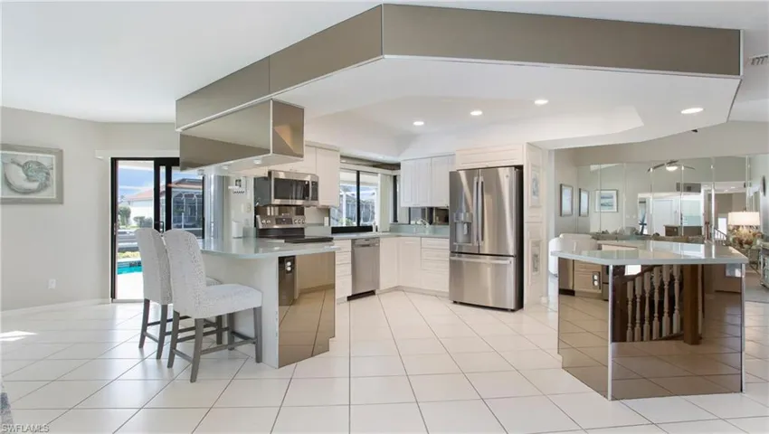 Kitchen featuring a kitchen bar, appliances with stainless steel finishes, light tile patterned floors, white cabinets, and a kitchen island