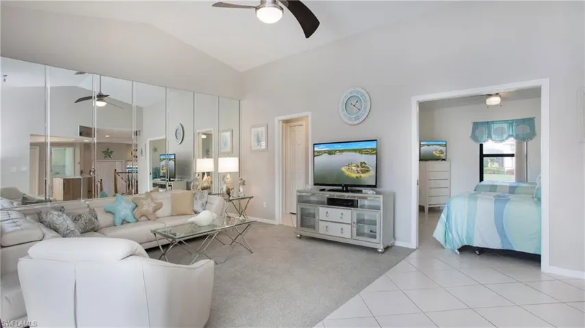 Living room featuring ceiling fan, light colored carpet, and vaulted ceiling