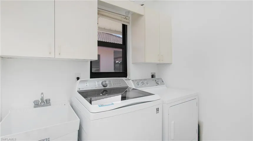 Clothes washing area featuring cabinets, washing machine and dryer, and sink