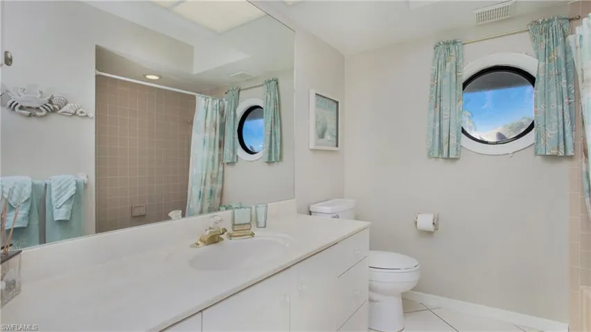 Full bathroom with tile patterned flooring, vanity, toilet, and shower / bath combo with shower curtain