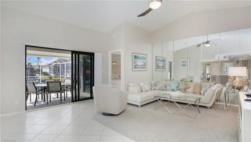 Tiled living room with ceiling fan and high vaulted ceiling