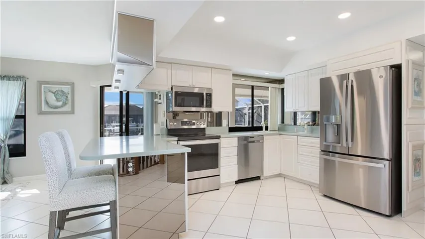 Kitchen featuring appliances with stainless steel finishes, white cabinetry, and plenty of natural light