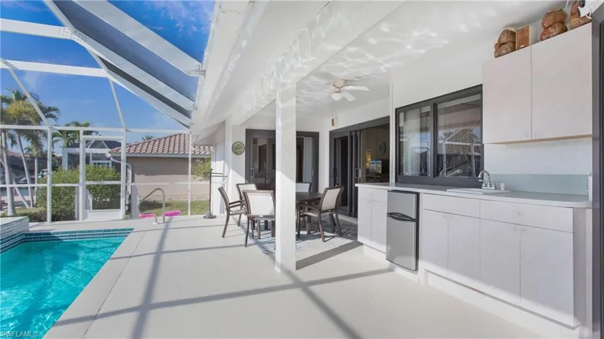 View of pool with a patio area, ceiling fan, glass enclosure, and a wet bar