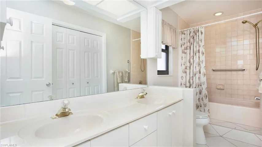 Full bathroom with tile patterned floors, vanity, shower / bath combo, and toilet