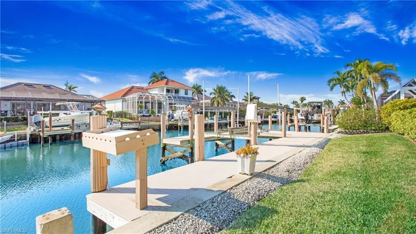 View of swimming pool with a water view, a dock, and a lawn