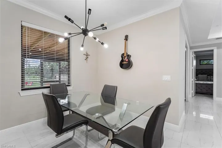 Dining space with a chandelier, crown molding, and light marble finish flooring