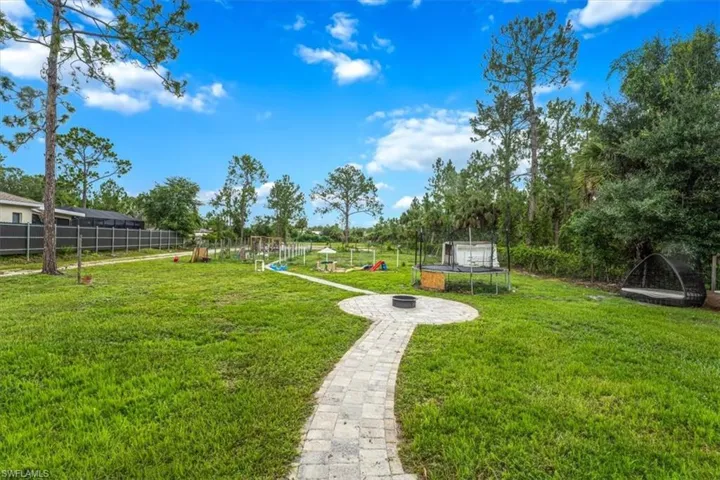View of green lawn with a trampoline and a fire pit