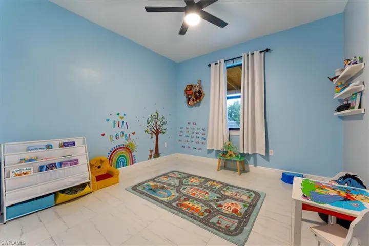 Game room featuring a ceiling fan and marble look tiles