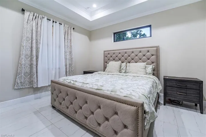 Bedroom with marble finish flooring, crown molding, a raised ceiling, and recessed lighting
