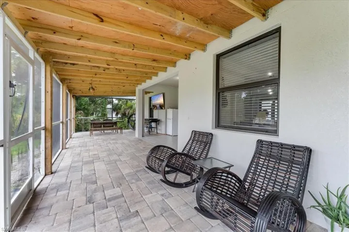 Sunroom / solarium with beam ceiling and stone finish flooring