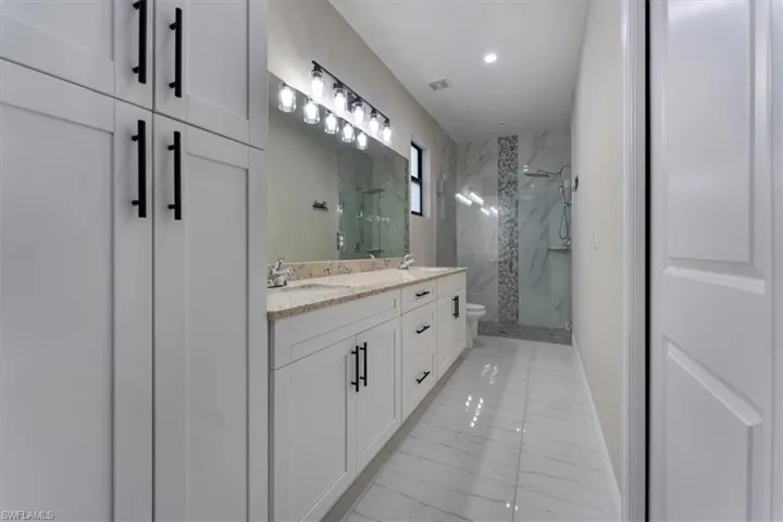 Full bathroom with a marble finish shower, double vanity, recessed lighting, and marble finish flooring