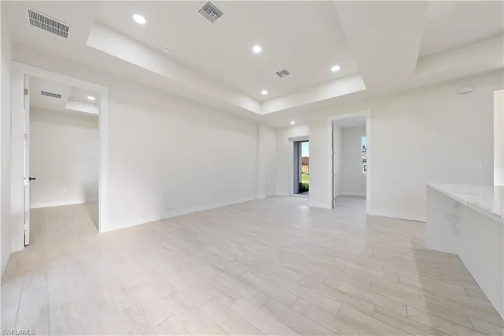 Empty room featuring a raised ceiling, recessed lighting, and wood finish floors