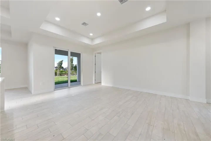 Empty room featuring a tray ceiling, wood tiled floors, and recessed lighting
