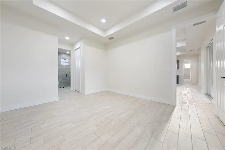 Empty room featuring a tray ceiling, wood finish floors, and recessed lighting