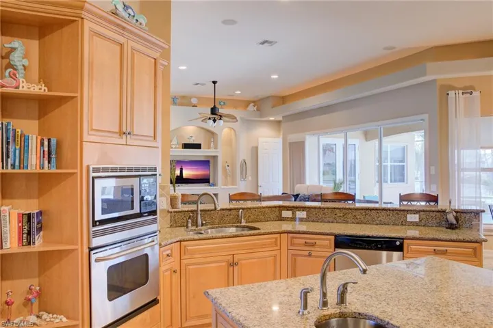 Kitchen featuring light stone counters, open floor plan, stainless steel appliances, and a sink