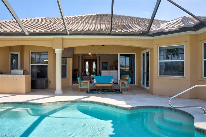 Back of house with an outdoor pool, stucco siding, a tile roof, a patio area, and french doors