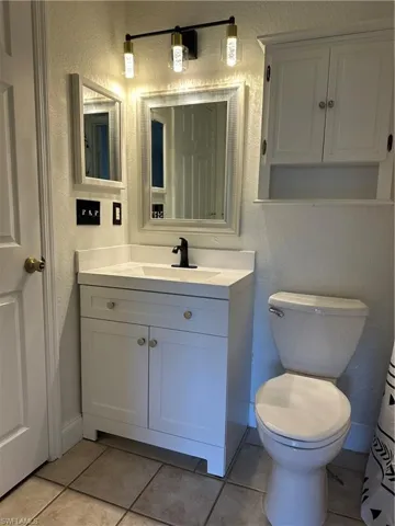 Bathroom featuring a white vanity with integrated sink, matte black faucet, and white framed mirror