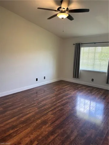 Spacious room featuring wood-finish flooring and a vaulted ceiling
