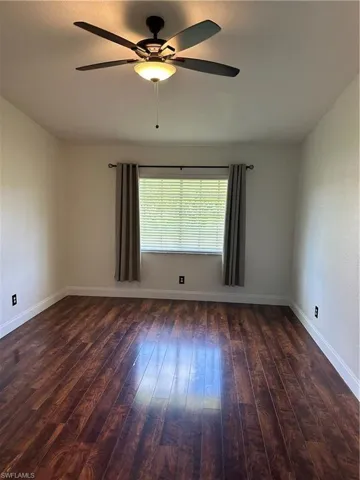 Room featuring wood-finish flooring, a window with blinds, a ceiling fan with integrated lighting, white baseboards, and neutral wall tones