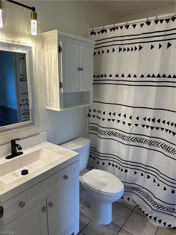 Bathroom featuring a white vanity with an integrated sink, matte black faucet, and a wall-mounted medicine cabinet