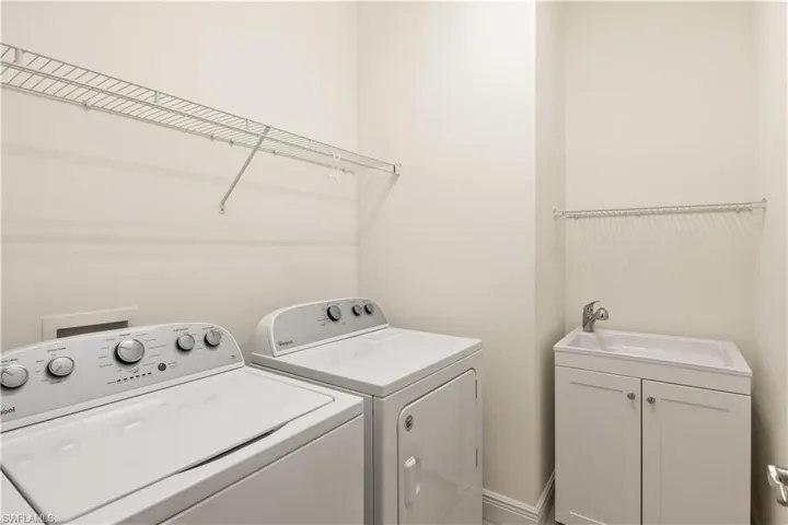 Spacious laundry room featuring storage space and a utility sink for added convenience.