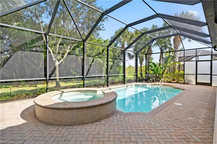 Screened-in pool and spa with preserve views, perfect for entertaining or relaxing.