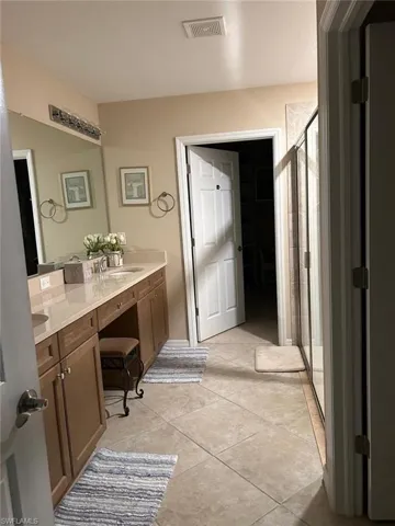 Full bathroom featuring a stall shower, double vanity, and light tile patterned floors